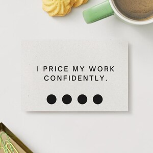 May include: A white card with the text "I PRICE MY WORK CONFIDENTLY." and four black dots. A cup of coffee with a green handle, a few biscuits, and a small gold tray with green paperclips are also visible.