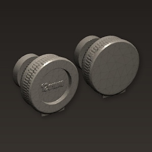 以下が含まれることがあります： 2つのグレーの12mmレンズキャップ。各キャップは、白いテキストで測定値が記載された、溝付きのエッジと平らな上面を備えています。キャップはカメラレンズを保護するように設計されています。