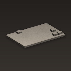 May include: A rectangular, textured, light gray object with three small, square blocks on one end and one on the other. The object is set against a dark gray background.