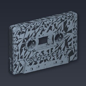 May include: A gray cassette tape with a geometric pattern of black triangles. The tape has two circular holes and a rectangular opening in the center. The cassette tape is a retro music storage device.
