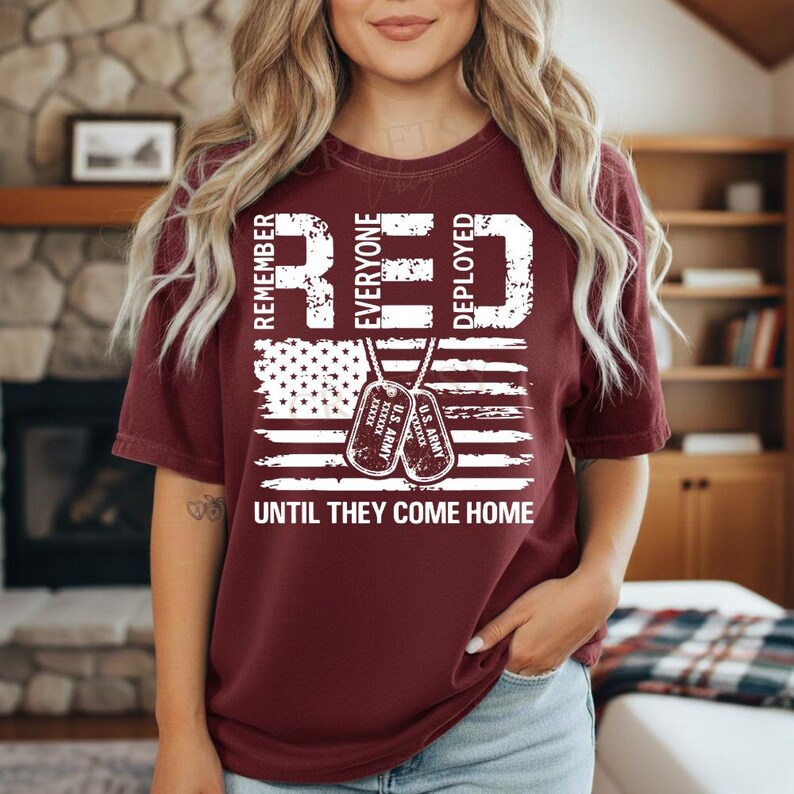 K&ouml;nnte beinhalten: Ein weinrotes T-Shirt mit einem verblassten Design der amerikanischen Flagge. Das Shirt zeigt die Worte "REMEMBER EVERYONE DEPLOYED" in wei&szlig;en Blockbuchstaben, zusammen mit zwei Erkennungsmarken und dem Satz "UNTIL THEY COME HOME."