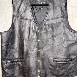 May include: A black leather waistcoat featuring a patchwork design of stitched leather panels, a V-neckline, and five brass-coloured snap buttons. The interior label reads Italian Stone Design GENUINE LEATHER. The waistcoat includes two front slit pockets.