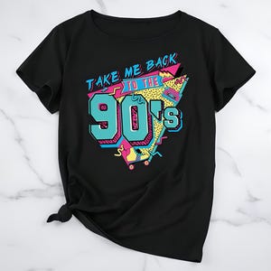 Puede incluir: Camiseta negra con un diseño gráfico colorido. El diseño presenta el texto "TAKE ME BACK TO THE 90's" en una fuente retro, con el número "90's" en color turquesa. El diseño incluye una cinta de cassette y formas geométricas.