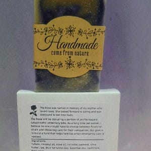 May include: A handmade soap bar in shades of dark green and brown, with a brown label saying "Handmade come from nature". The soap sits on a white box with product information. The soap is made with natural ingredients.