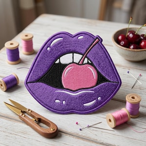 May include: Embroidered purple lips patch with a pink cherry inside. The patch is surrounded by sewing supplies, including spools of thread in pink and purple, scissors, and pins. A small bowl of cherries is in the background.