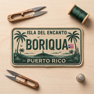 May include: Embroidered patch featuring the words "Isla Del Encanto Boriqua Puerto Rico" with palm trees, a lighthouse, and the Puerto Rican flag. The patch is surrounded by green thread, with a tan background. Also pictured are a pair of scissors, a spool of green thread, and a thimble.