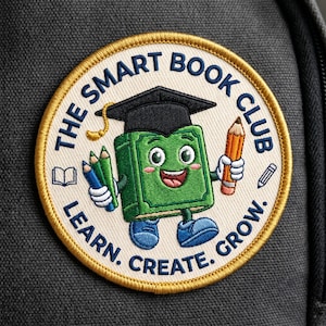 May include: A circular embroidered patch with a cream background and gold border. It features a green book character wearing a black graduation cap, holding a pencil and green markers. Text reads: THE SMART BOOK CLUB. LEARN. CREATE. GROW.