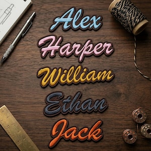 May include: Embroidered name patches in various colors: light blue "Alex", pink "Harper", yellow "William", navy "Ethan", and orange "Jack". Each patch has a brown border and is displayed on a wooden surface, with sewing supplies in the background.
