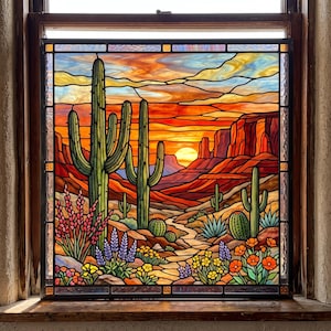 May include: A square stained glass window panel depicting a desert landscape at sunset. The scene features tall saguaro cacti, smaller round cacti, and colorful wildflowers in the foreground, with red rock formations and a bright sun in the background.