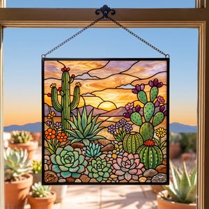 May include: A square stained glass panel featuring a desert landscape at sunset. The scene depicts a tall saguaro cactus, a prickly pear cactus with purple fruit, and various succulents in shades of green and pink. The background shows mountains.