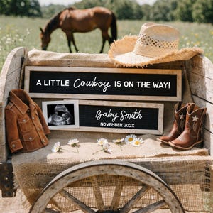 Pode incluir: Uma carroça rústica exibe um anúncio de bebê com tema de cowboy. A cena inclui um chapéu de cowboy de palha, botas de couro marrom e uma jaqueta de camurça. O texto diz "A Little Cowboy is on the Way!" e "Baby Smith, November 202X."