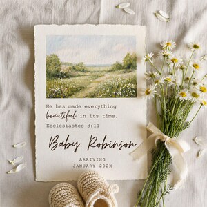 Puede incluir: Una tarjeta de anuncio color crema con una escena de paisaje en acuarela, el texto "Él ha hecho todo hermoso a su tiempo. Bebé Robinson llega en enero de 202X" y un ramo de margaritas. Un par de patucos para bebé en la parte inferior.
