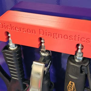 May include: A bright orange rectangular tool holder with the text Dickerson Diagnostics embossed on the front. The holder features three vertical slots, each containing a metallic air blow gun nozzle attached to a black handle tool.