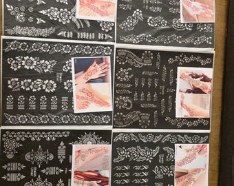 May include: Six rectangular black sheets featuring intricate white floral and geometric henna stencil patterns. Each sheet includes a small color photograph demonstrating the applied design on skin, with the text Sheikh Umair printed on each.