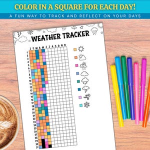 May include: A white weather tracker chart with the text "COLOR IN A SQUARE FOR EACH DAY!" and "A FUN WAY TO TRACK AND REFLECT ON YOUR DAYS". The chart has a grid for tracking weather, with colorful markers and a cup of coffee on a wooden surface.