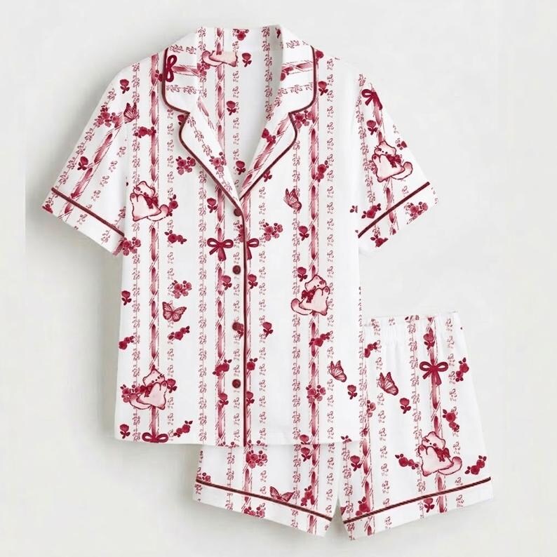 May include: White pyjama set with a red floral and butterfly pattern. The short-sleeved top has a button-down front and a notched collar. The shorts have a matching print and a comfortable fit. The set is trimmed with red piping.