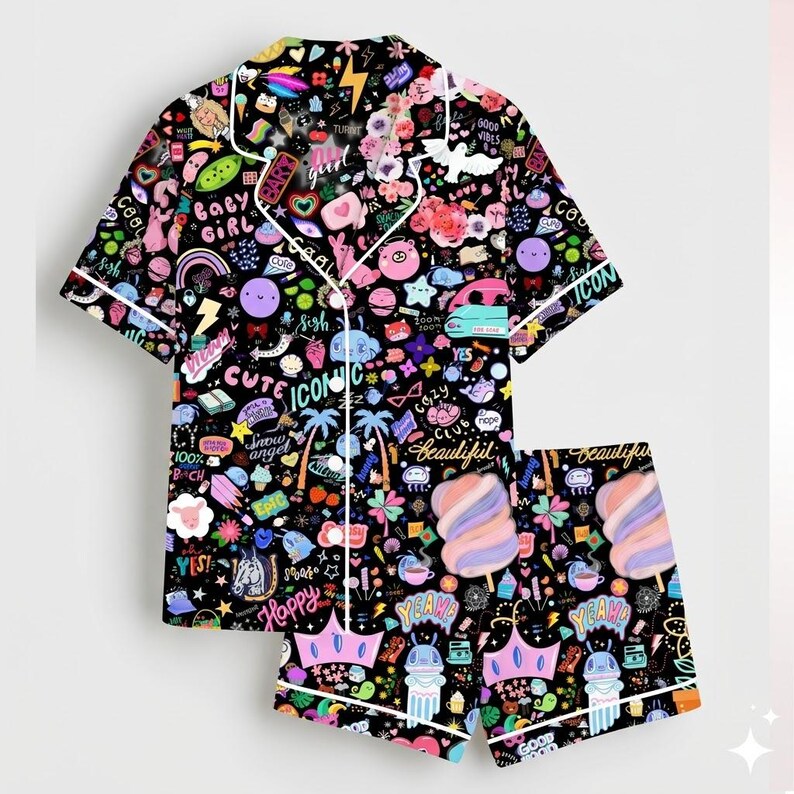 May include: Black pajama set with a vibrant print of colorful icons, text, and illustrations. The set includes a short-sleeved button-up shirt and matching shorts, both trimmed with white piping. The design features words like "Cute", "Happy", and "Beautiful".