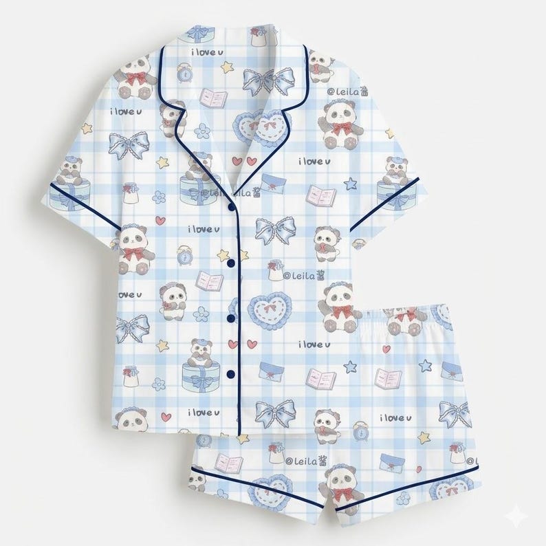 May include: Light blue pajama set with a white plaid pattern, featuring panda bears, bows, hearts, and books. The short-sleeved top and shorts have dark blue trim and the text "i love u".