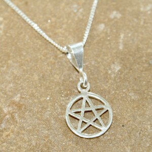 May include: A silver chain necklace with a silver pendant featuring a five-pointed star inside a circle.