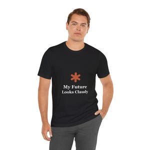 May include: Black crew neck t-shirt with the text "My Future Looks Claudy" in white font. Above the text is an orange asterisk symbol. The shirt is made of a soft material.