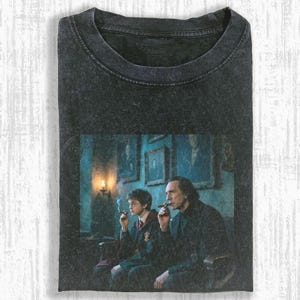 May include: Dark gray t-shirt featuring a scene with two people smoking cigars. The image is a movie still with a vintage, distressed look. The shirt has a crew neck and short sleeves. The graphic is a movie scene.