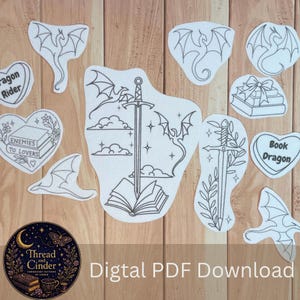 Puede incluir: Una colección de pegatinas de arte lineal en blanco y negro con dragones, espadas, libros abiertos y diseños en forma de corazón con el texto Dragon Rider, Enemies to Lovers y Book Dragon, junto a un logo circular de Thread and Cinder.