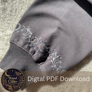 Peut inclure: Manche de sweat-shirt grise avec broderie de croissants de lune et motifs floraux bleus clair et blancs. Le texte "Digital PDF Download" est visible. Le design est de Thread and Cinder Embroidery Patterns.