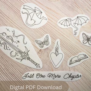 May include: A white ceramic mug with a black handle and the text "But First, Coffee" in a black, handwritten-style font. The mug is on a white surface.