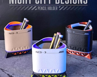 May include: Three pencil holders with a futuristic design. The holders are in beige, white, and black, each with a different color accent. The text "NIGHT CITY DESIGNS" and "PENCIL HOLDER" are at the top. Each holder has the text "NCD-3".