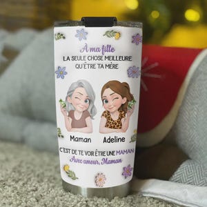 May include: A white insulated tumbler with a black lid, featuring a floral design and the text "A ma fille, LA SEULE CHOSE MEILLEURE QU'ÊTRE TA MÈRE." It includes illustrations of a mother and daughter, with the names "Maman" and "Adeline."