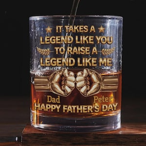 May include: A clear whiskey glass with a gold inscription that reads "IT TAKES A LEGEND LIKE YOU TO RAISE A LEGEND LIKE ME." The glass has two gold fists and the words "Dad" and "Peter" with "HAPPY FATHER'S DAY" below.