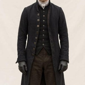 May include: A person wearing a dark gray coat with large buttons, a matching vest, and brown pants. The person is also wearing a brown tricorn hat and black gloves. The outfit is reminiscent of historical attire.