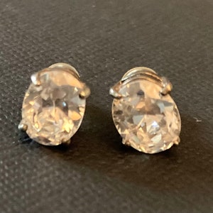 May include: A pair of silver earrings with clear oval-shaped cubic zirconia stones.