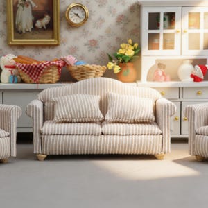 May include: Miniature living room set with a beige and white striped sofa and matching armchairs. The sofa has two pillows. The room includes a white cabinet, a painting, and decorative items. The overall theme is a cozy, dollhouse-style interior.
