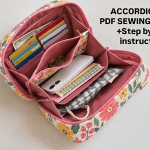 May include: An open accordion bag with a floral print exterior featuring pink, yellow, and green flowers on a cream background. The interior is lined with pink fabric and contains multiple compartments holding cards, a phone, and a small pouch. Text reads: ACCORDION BAG PDF SEWING PATTERN +Step by step instructions.