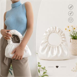 May include: A white satin handbag with a gathered, ruched texture and a circular integrated handle. The bag features a soft, lustrous finish and a curved, crescent-like silhouette. The design is simple, focusing on the gathered fabric detail.