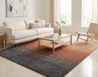 May include: A rectangular area rug featuring a gradient color transition from dark charcoal gray at one end to a warm burnt orange at the other. The rug has a textured, low-pile surface and is positioned on a light-colored tiled floor.