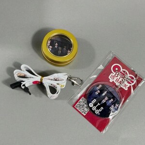 May include: A collection of BTS merchandise, including a round tin, a lanyard, and a keychain. The tin is gold with a clear window showing a photo. The lanyard is white with a printed design. The keychain is round with a photo and the text "BTS IS BACK".