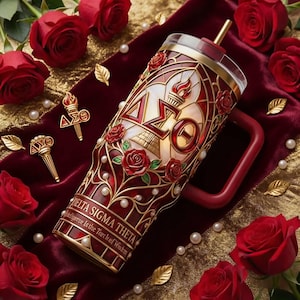 May include: A red and gold tumbler with the Delta Sigma Theta sorority letters and symbols. The tumbler features a stained-glass design with red roses and pearl accents. The handle and straw are red.