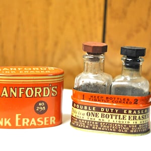 May include: A vintage tin of Sanford's Ink Eraser, No. 298, with two small glass bottles inside. The bottles are labeled "Keep Bottles Tightly Corked". The tin is orange with black lettering and a yellow stripe.