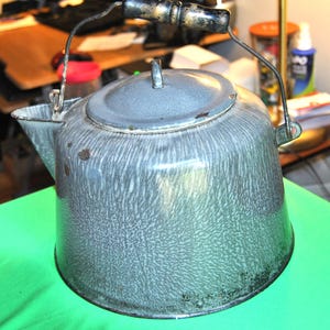 May include: A vintage gray speckled enamel tea kettle with a wooden handle and a wire bail handle.