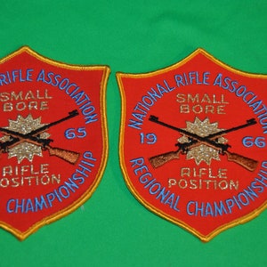 Op de afbeelding: Twee rode, goudomrande patches met de tekst "National Rifle Association" en "Small Bore Rifle Position Regional Championship" met de jaren 1965 en 1966.
