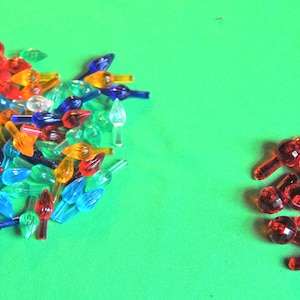 Może przedstawiać: Duży wybór kolorowych żarówek choinkowych w różnych kształtach i rozmiarach, w tym czerwone, zielone, niebieskie, pomarańczowe i żółte. Jest też mniejsza grupa czerwonych żarówek.