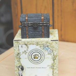 以下が含まれることがあります： 白のセラミックマグカップ、黒いハンドル、手書き風の「But first, coffee」の文字。マグカップは白い面に置かれています。マグカップの高さは10cmです。
