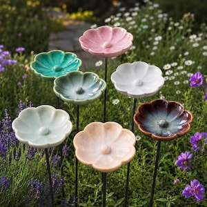 Peut inclure: Un ensemble de sept tuteurs de jardin en céramique en forme de fleur, chacun doté d'une finition émaillée unique dans des tons rose, bleu sarcelle, bleu clair, blanc, pêche et un mélange bleu et marron, montés sur de fines tiges métalliques.