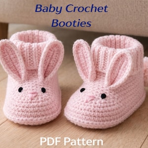 May include: A pair of pink crochet baby booties shaped like bunnies. The booties have long ears, black eyes, and a pink nose. The text "Baby Crochet Booties" and "PDF Pattern" are displayed in the image.