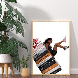 May include: A framed art print featuring a stylish illustration of a person in a black outfit and sneakers, leaning on a stack of fashion books. The book titles include "Dior", "Chanel", and "Louis Vuitton". A splash of red liquid adds a dynamic element.