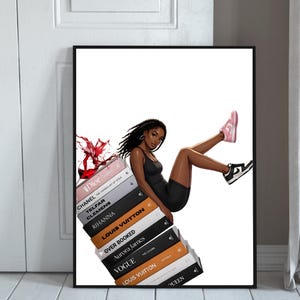 May include: A framed art print featuring a stylish illustration of a person in a black outfit, leaning against a stack of fashion books. The books include titles like Dior, Chanel, and Louis Vuitton. The person is wearing pink and black sneakers. A splash of red liquid is seen.