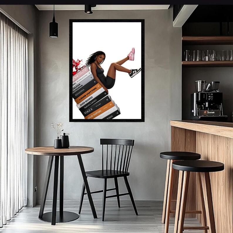 May include: A framed art print depicts a person in a black dress and sneakers, reclining on a stack of fashion books. The books include titles like "Vogue" and "Louis Vuitton." The artwork is displayed in a modern interior with a round table and black chair.
