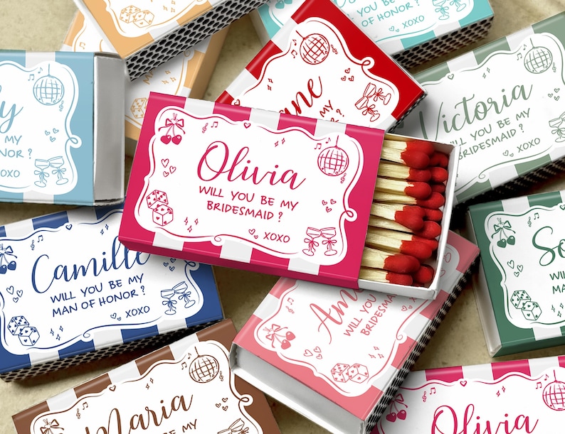 May include: A collection of personalized matchboxes in various colors, including pink, blue, and green. Each box features a name and the text "Will you be my bridesmaid?" or "Will you be my man of honor?" with decorative elements.